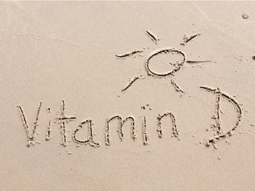 the words vitman d and a picture of the sun written on the sand - a blog about symptoms of low vitamin d.