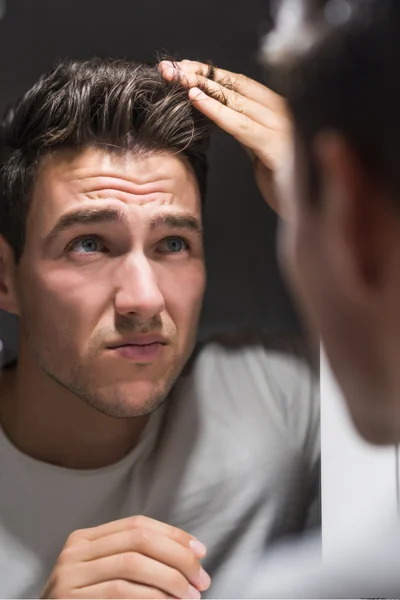 Mens category - male combing through his hair looking for hair loss improvement